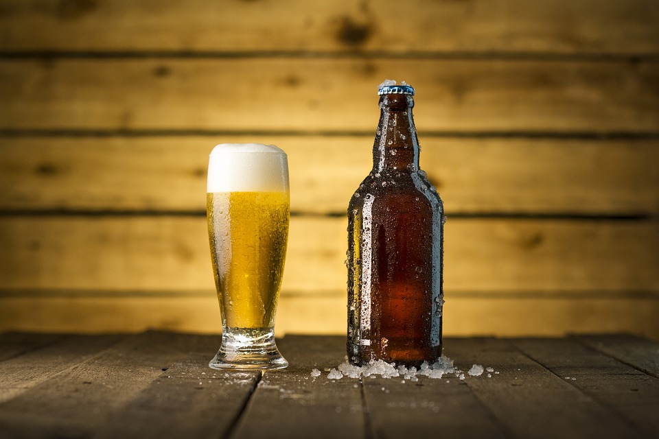 A beer bottle and a large mug filled with beer on a dark wooden table. | Craft beer near Bentonville, AR.
