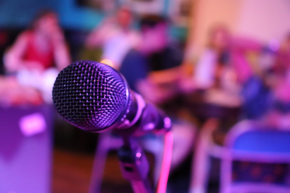 Close view of a microphone on a stage with people seated in the background. | Date night around Bentonville, AR.