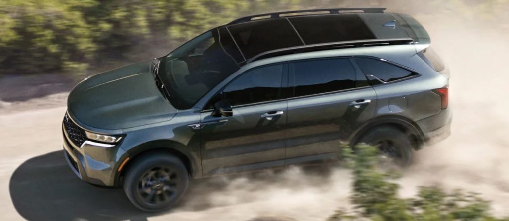 A dark greenish-gray 2022 Kia Sorento being driven on a dirt road. | Kia dealer in Bentonville, AR.