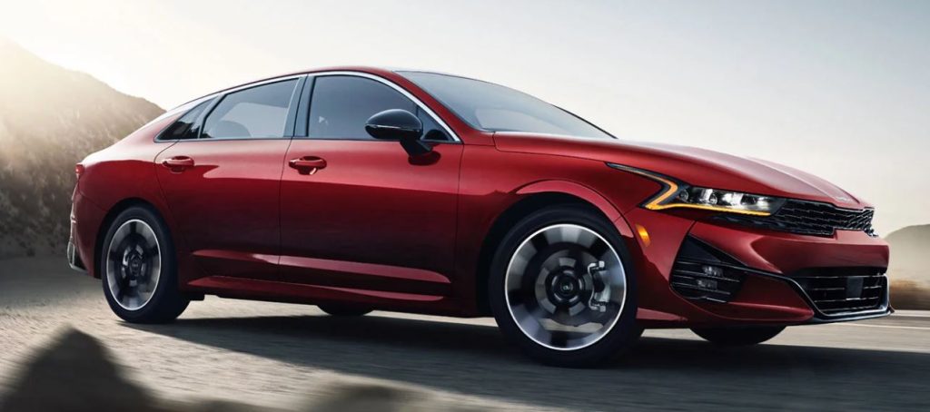 Profile view of a red 2022 Kia K5 being driven. | Kia dealer in Bentonville, AR.