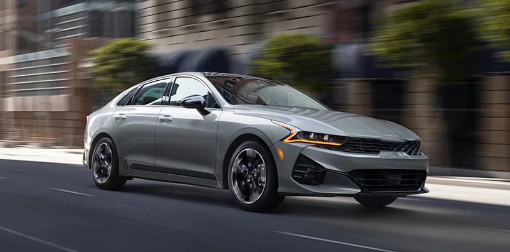A silver 2022 Kia K5 being driven on the highway. | Kia dealer in Bentonville, AR.