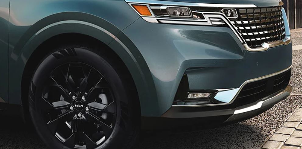 Close view of the grille area of a turquoise 2022 Kia Carnival. | Kia dealer in Bentonville, AR.