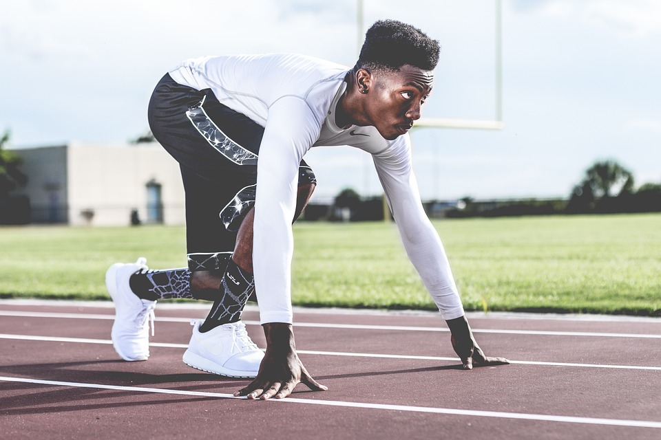 A runner crouched down on the track preparing to run. | Sports and stadiums near Bentonville, AR.