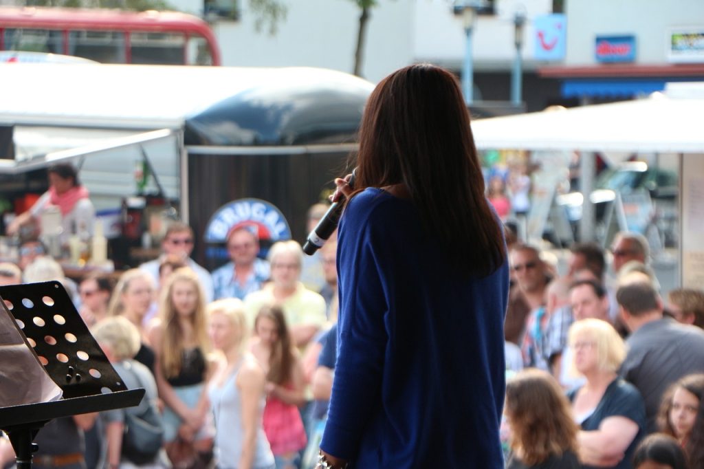 A woman performing on stage with onlookers in front of her. | Spring activities in Bentonville, AR | Crain Kia of Bentonville
